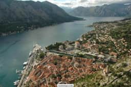 Historic view across Kotor roofs toward the mountain fortifications