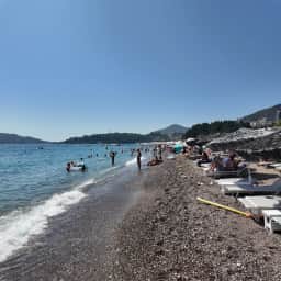File di lettini allineati sulla riva di ciottoli della spiaggia di Bečići.