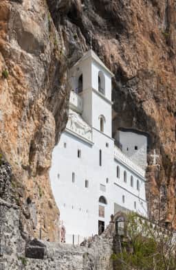 Pilgrims on the final paved stretch below the Upper Monastery at Ostrog, with the whitewashed cliff church above them