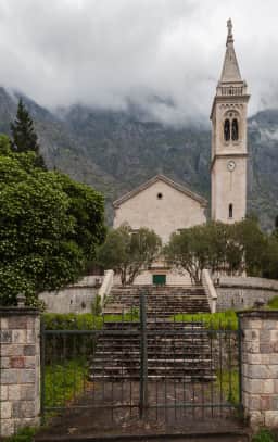 The stone church of St Eustace in Dobrota, its bell tower rising above the shoreline settlement.