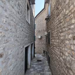 Una callejuela empedrada del casco antiguo de Herceg Novi, entre casas de contraventanas cerradas, que baja hacia el mar.