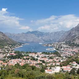 Large panorama sur les bouches de Kotor, la ville déployée le long du rivage au pied de montagnes abruptes.