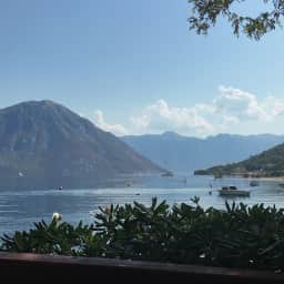 The inner Bay of Kotor from a Morinj terrace, oleander in front and the Perast shore across the water