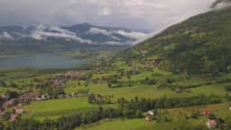 Aerial view over the Plav valley, with the town and its lake basin ringed by high mountain slopes.