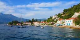 Rose harbour with small boats, stone houses and mountains across the bay