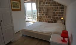 Bedroom with exposed stone wall and terrace door in the Klinci 2014 gallery