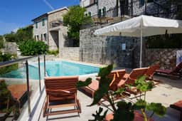 Pool terrace beside restored stone buildings at Klinci Village Resort