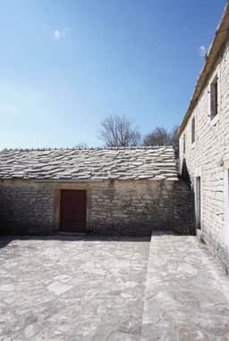 Cortile lastricato in pietra e tetto basso a lastre a Žlijebi