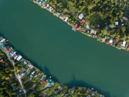 Veduta aerea del fiume Bojana tra sponde alberate e case sul fiume