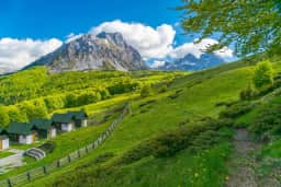 Cabins and pasture beneath a rocky Komovi summit