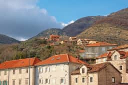 Stone waterfront houses in Kamenari below a steep mountain slope