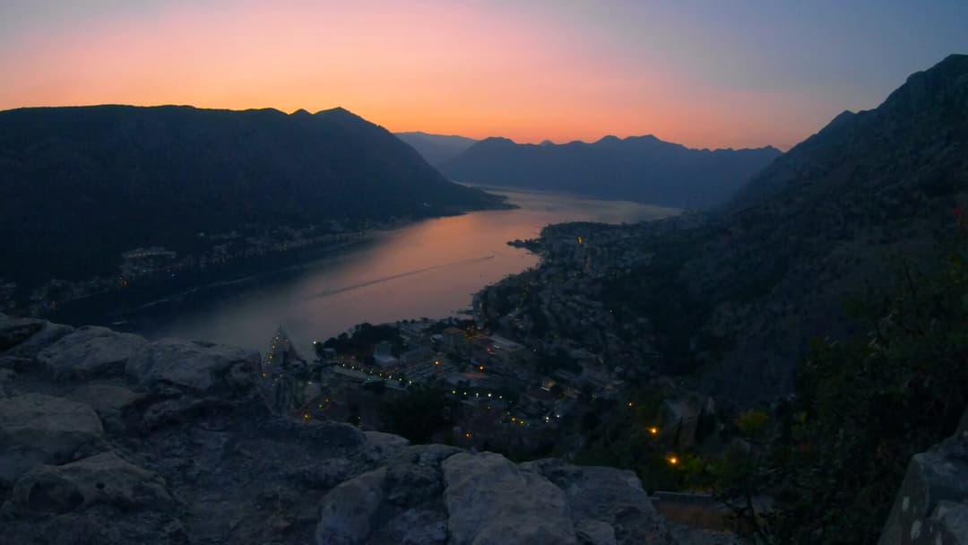 Sunset over the Bay of Kotor seen from San Giovanni Fortress, with city lights beginning to glow
