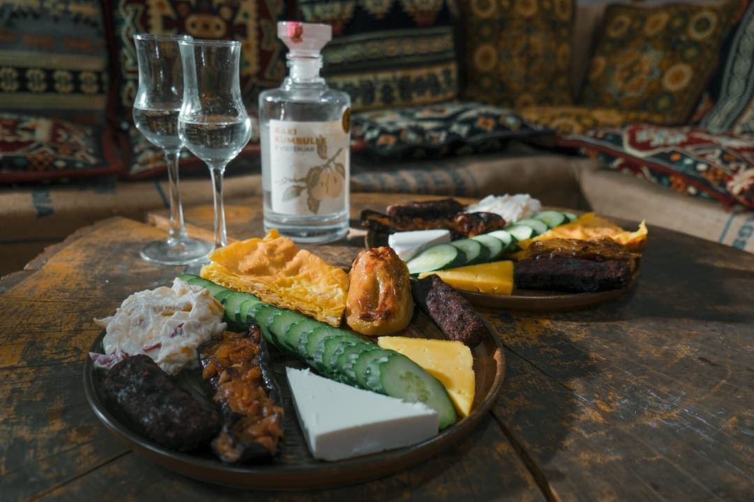 Traditional Montenegrin food platter with rakija glasses on a wooden table in a stone-walled konoba
