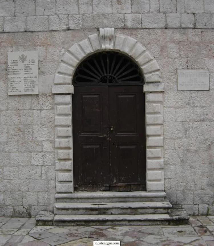 Porte de bois sombre dans un arc de pierre en plein cintre avec de larges marches de seuil