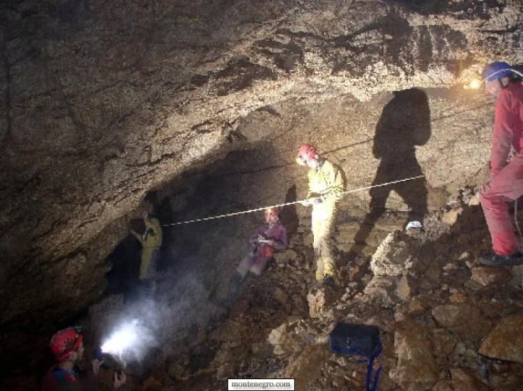 Legacy caving expedition member beside pale limestone formations