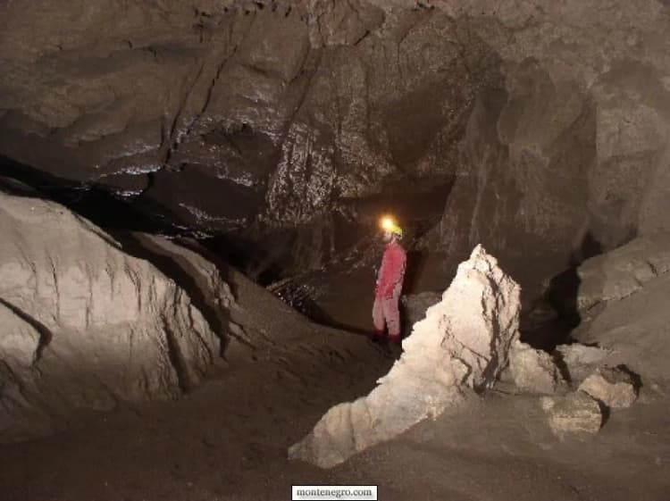 Two legacy expedition cavers beside layered cave rock