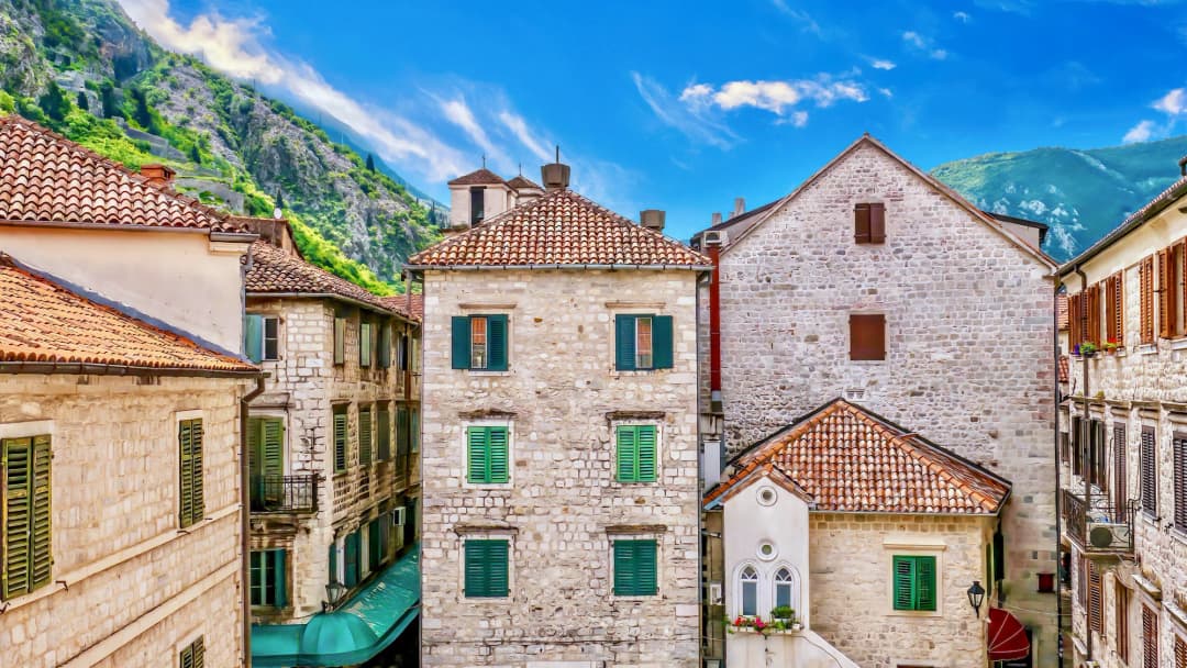 A traditional Montenegrin dry-stone house with a heavy stone roof standing in open upland terrain.
