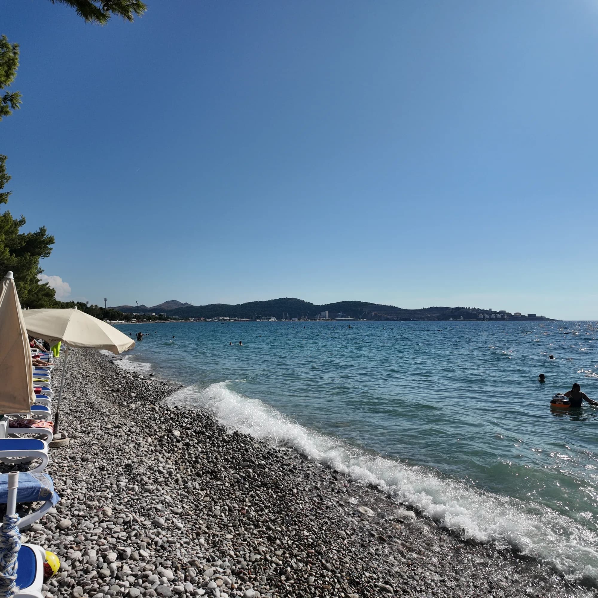 Pebbles, sunbeds and the open bay at Žukotrlica beach, Bar