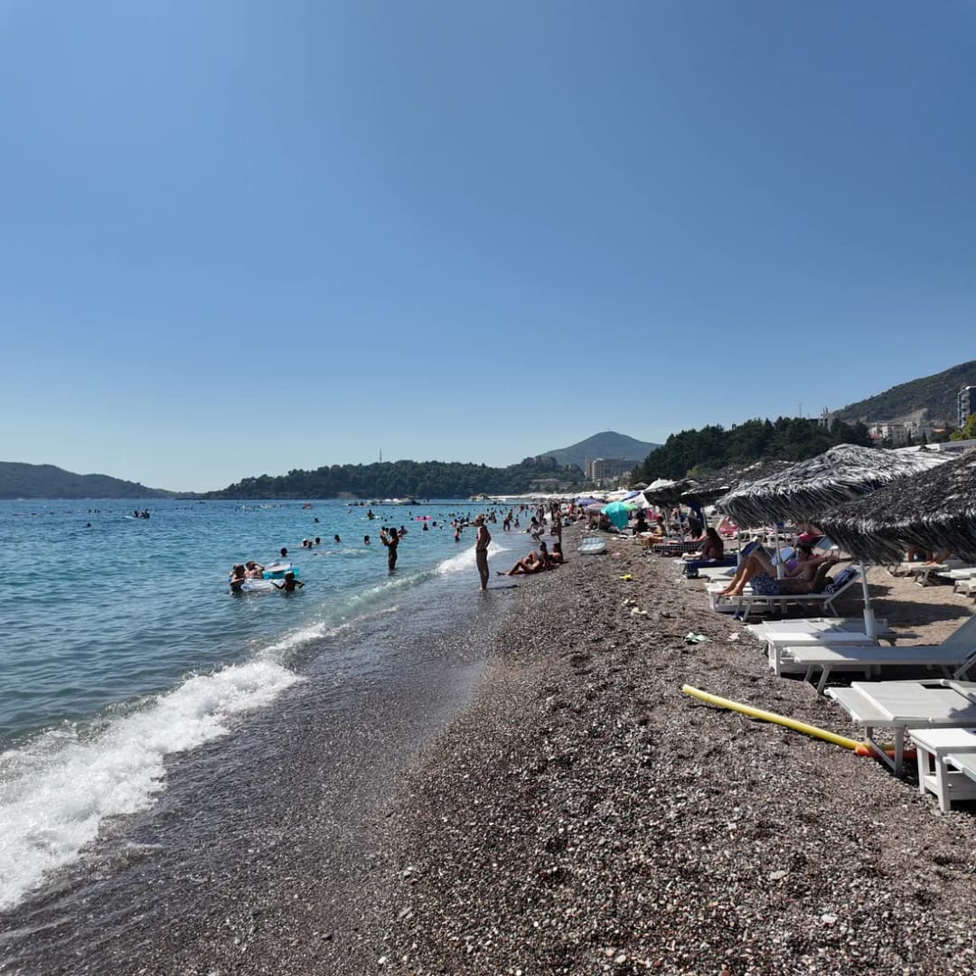 Rows of sunbeds lined up on the pebble shore at Bečići beach.