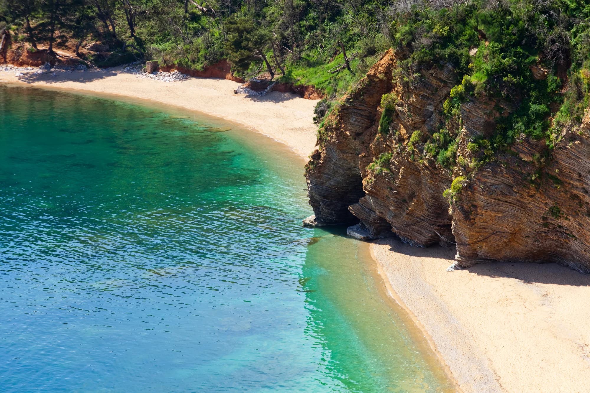 The folded rock between the two Mogren coves from above, green shallows turning to blue off the sand