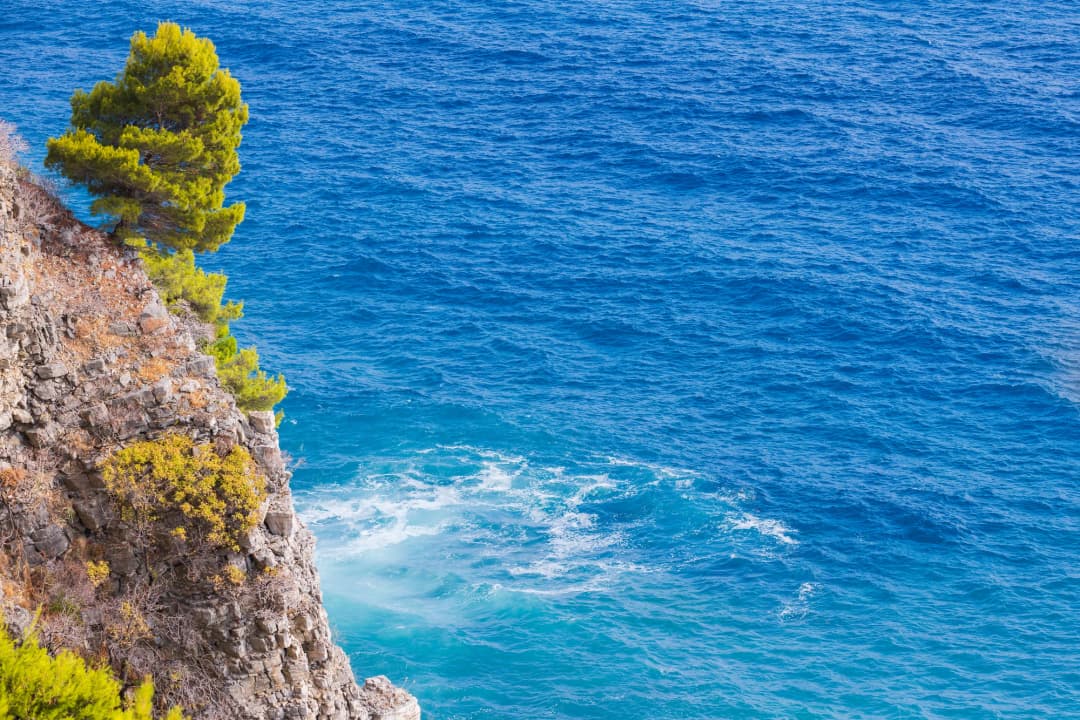 Prizor objedovanja uz more u selu Pržno, koji prikazuje stolove postavljene na plaži sa ribarskim čamcima u blizini i Jadranskim morem u pozadini