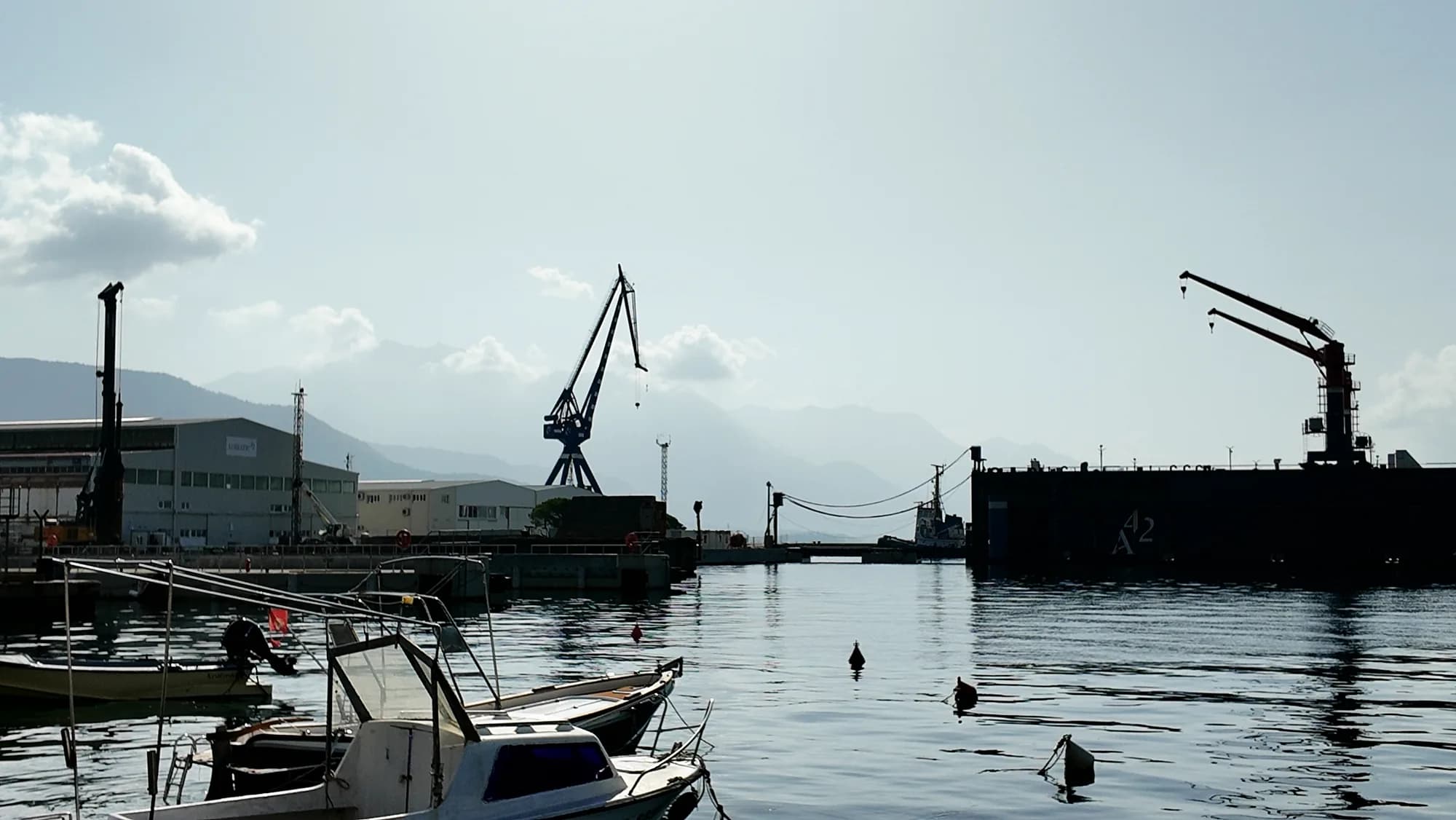 Werftkräne über dem Wasser bei Bijela, kleine Boote im Vordergrund