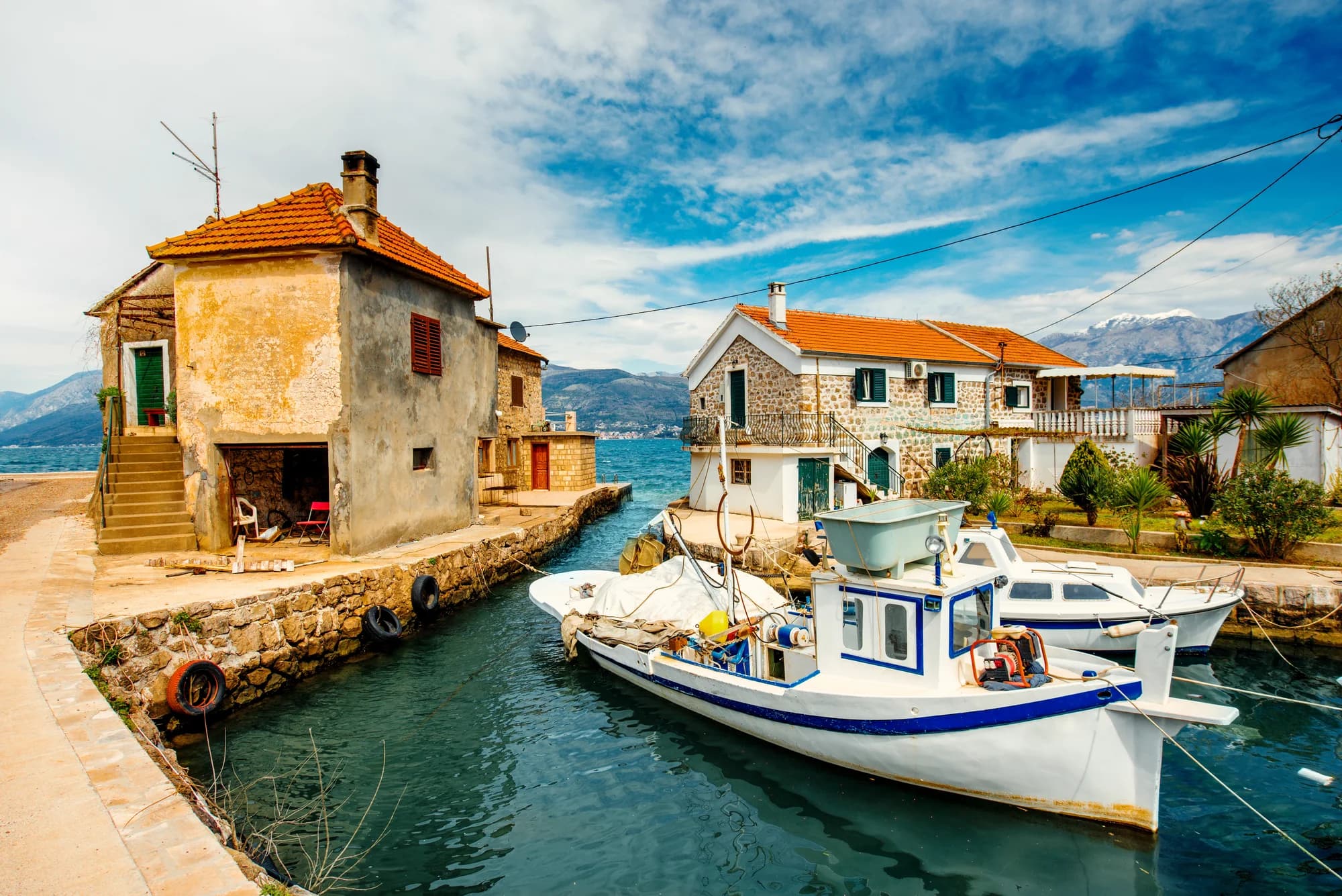 Stone houses either side of the sea channel at Bjelila, fishing boats moored in it