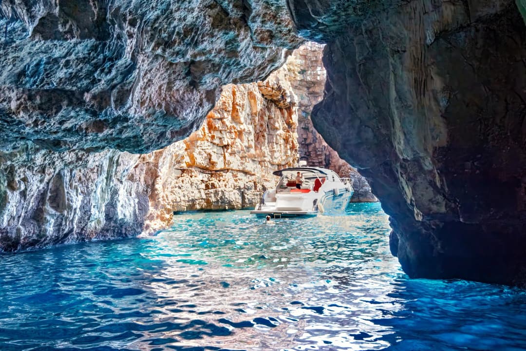 The limestone arch of the Blue Cave with a boat moored beneath it