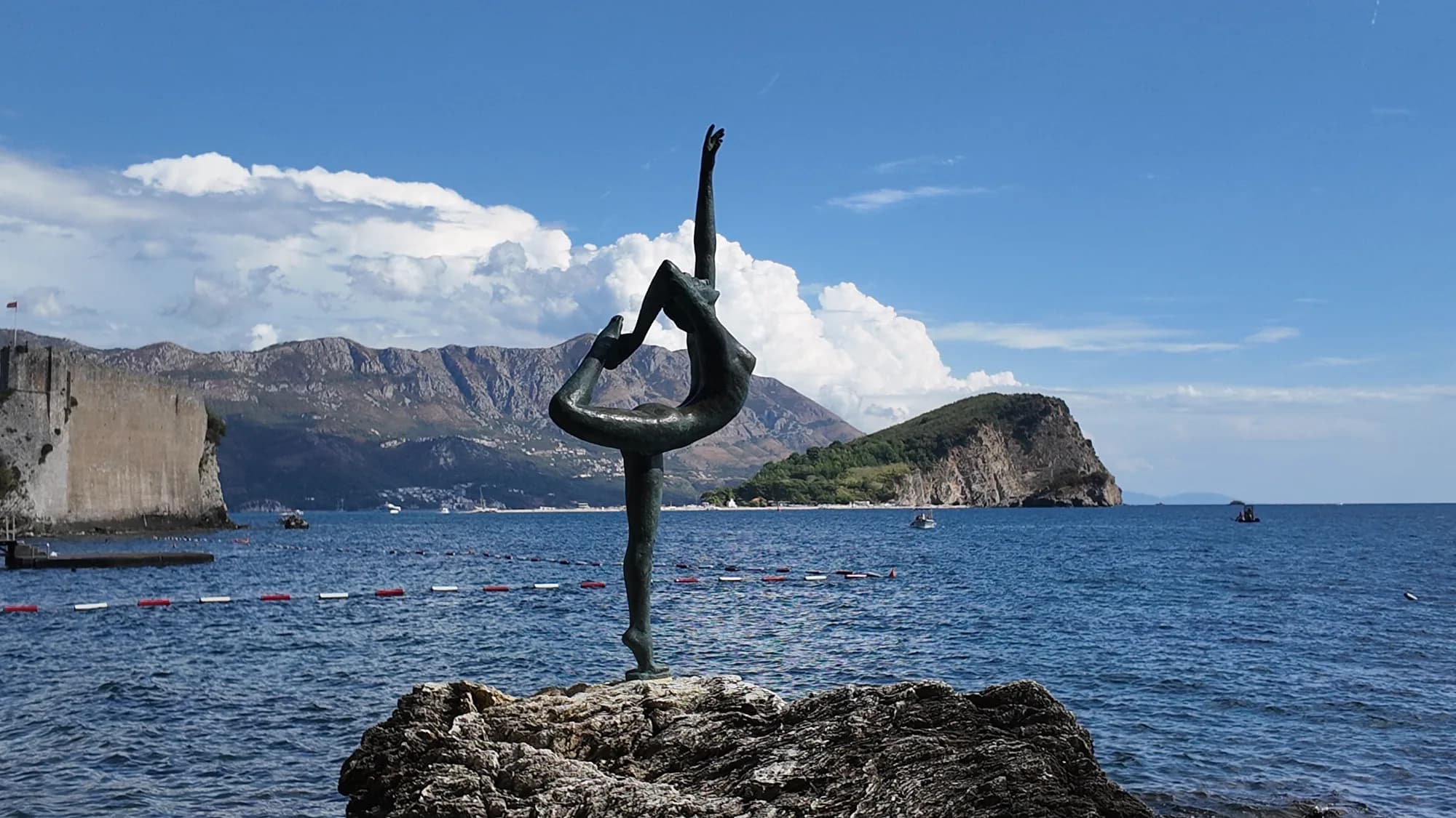 The Ballerina statue on her rock, with the Old Town walls and the island of Sveti Nikola behind