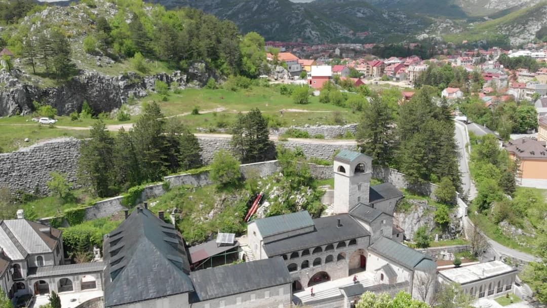 Cetinje distesa nella sua conca pianeggiante cinta dai monti, con i tetti bassi della città vecchia sotto i nudi pendii carsici.