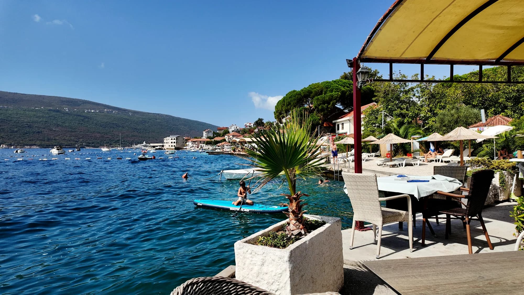 A restaurant terrace over clear water at Đenovići