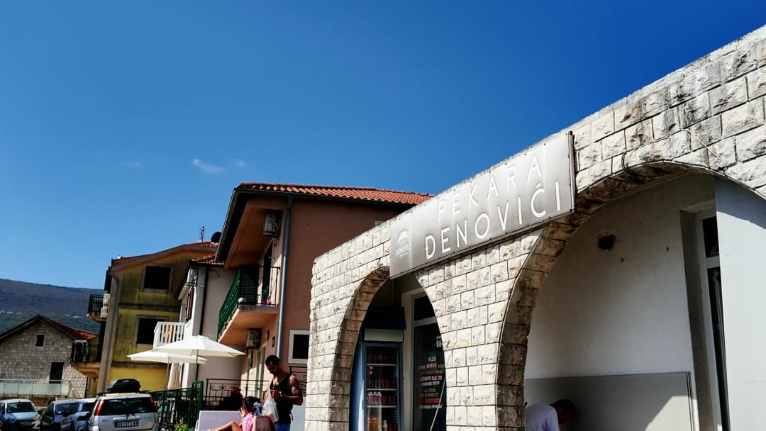 Obala u Đenovićima, gdje se uske plaže spajaju s obalnim zidovima i betonskim kupališnim pristaništima duž zaliva.