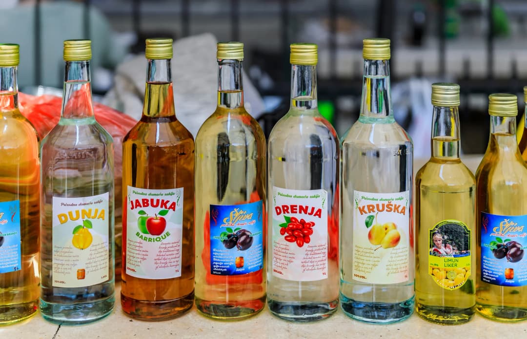 Unutrašnjost tradicionalne konobe s kamenim zidovima i otkrivenim drvenim gredama, bačvama vina uzduž jednoga zida, postavljenim stolom s tradicionalnim jelima i toplim ambijentalnim osvjetljenjem