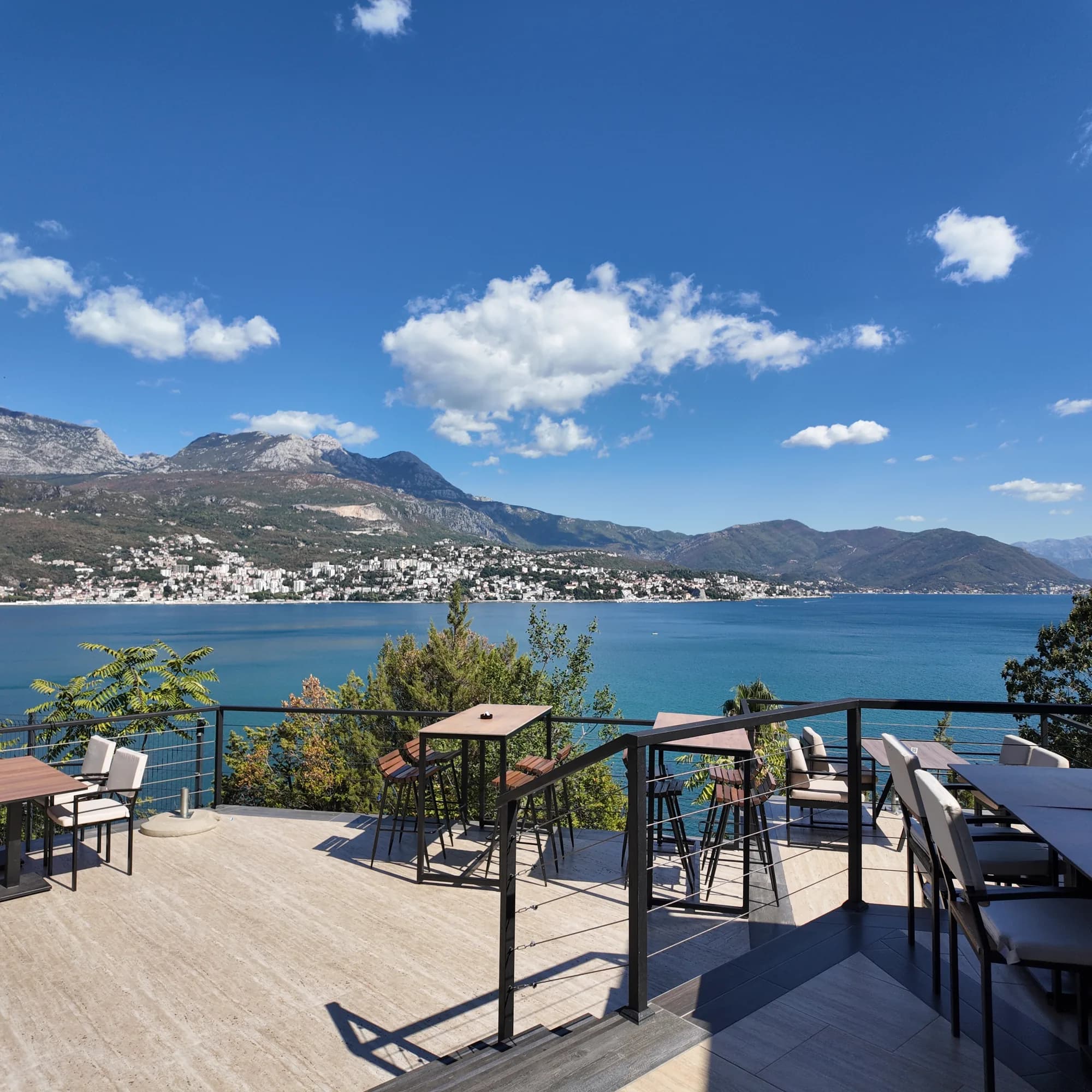 Herceg Novi oltre l’acqua, dalla terrazza di un caffè a Njivice, con la parete dell’Orjen alle spalle della città