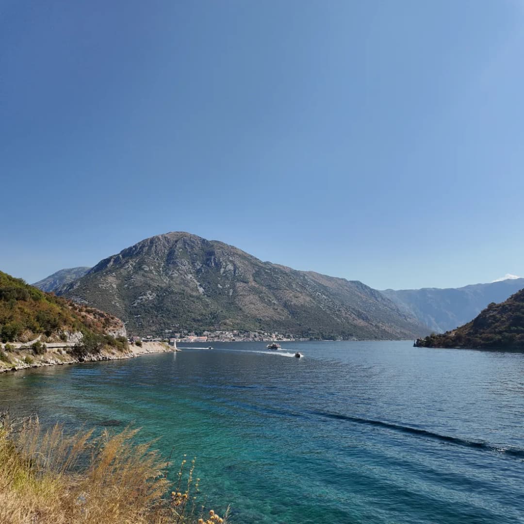 The Verige narrows seen from Kamenari, where the bay pinches to its tightest point and the far shore rises steeply from the water.