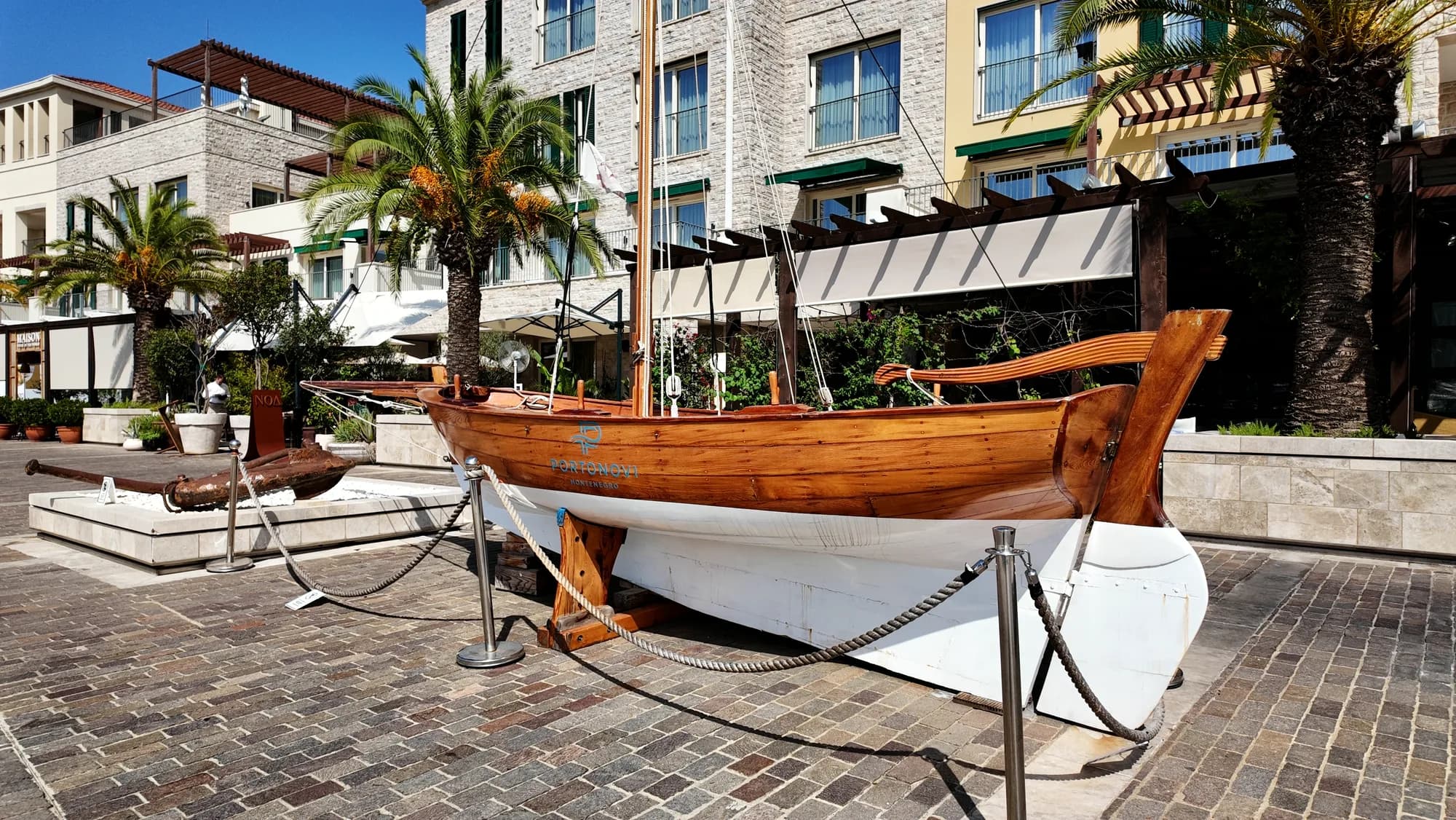 Ein hölzernes Boot auf der Promenade von Portonovi, zwischen Palmen