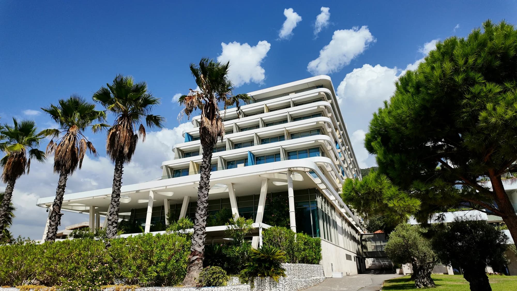 Das Resorthotel und seine Palmen an der Küste von Kumbor
