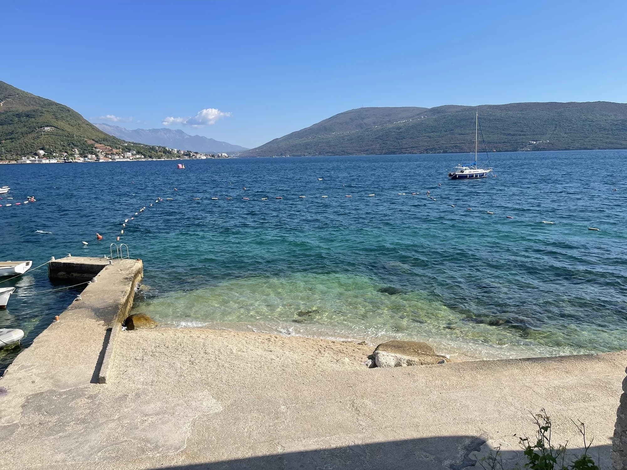 The buoyed swimming area at Meljine with a small stone pier and the inner bay beyond