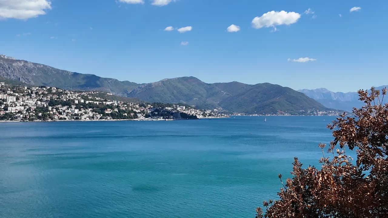 The open bay from the Njivice shore, Herceg Novi and Igalo strung along the far side under the Orjen massif