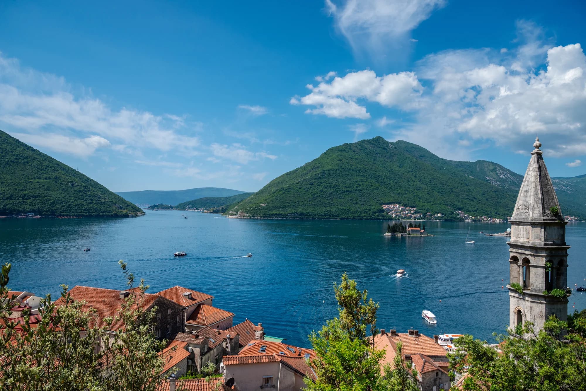 Blick die Bucht entlang von Perast, der Glockenturm von St. Nikolaus im Bild