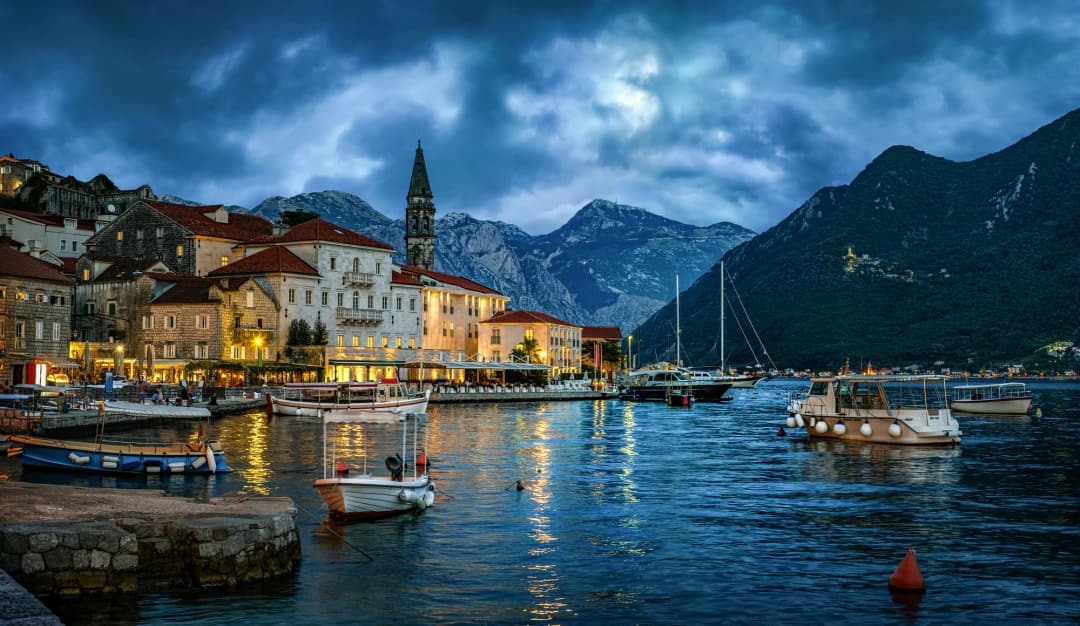 Perast's illuminated stone waterfront and palaces at dusk on the Bay of Kotor