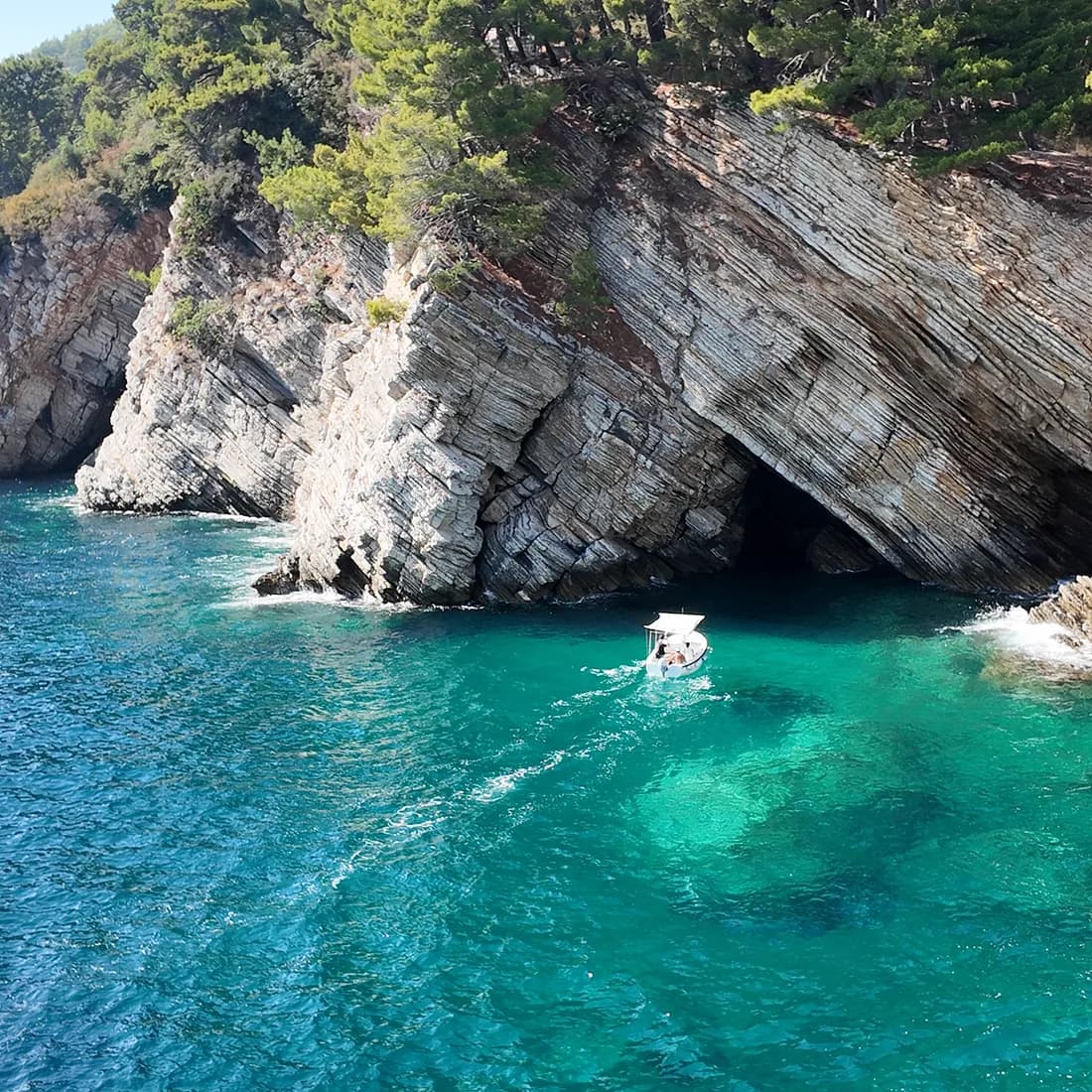 A boat below the cliffs and sea cave on the headland south of Petrovac