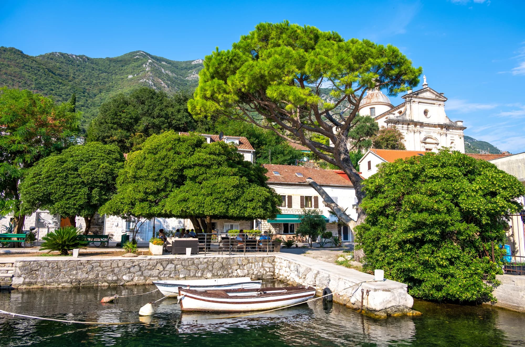 Vertäute Boote unter einer Kapelle am Ufer von Prčanj