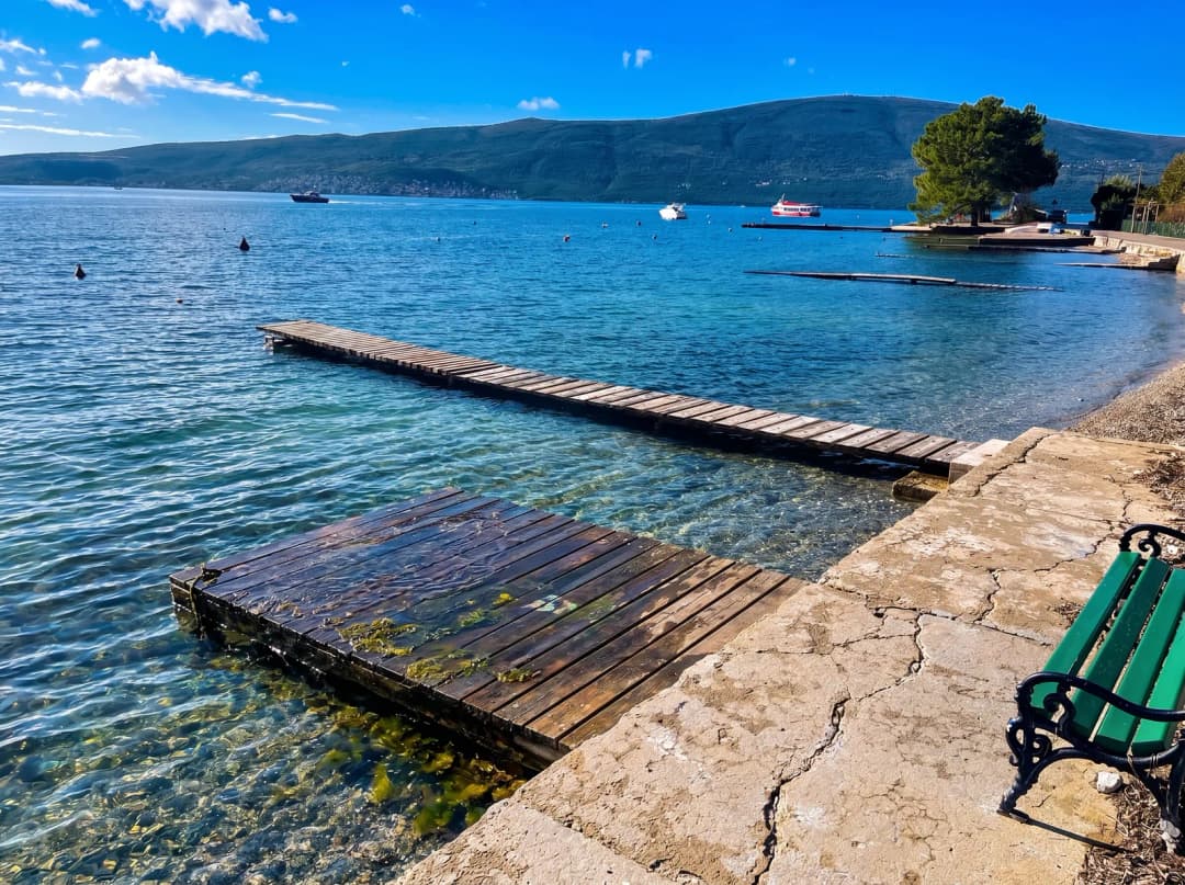 A quiet jetty on the Bijela shore with the steep mountains of the bay rising behind it.