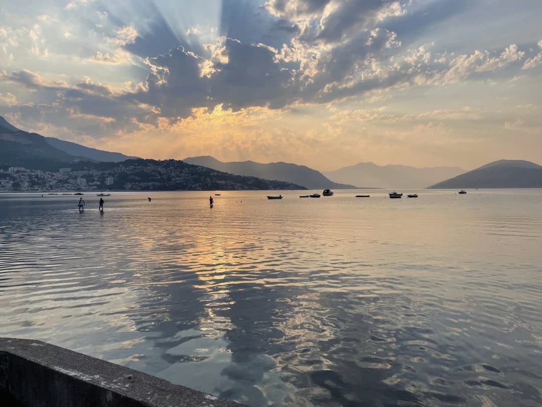 La baia poco profonda di Igalo al tramonto: acqua calma che si estende a lungo su un fondale digradante, con le colline che si scuriscono alle spalle.