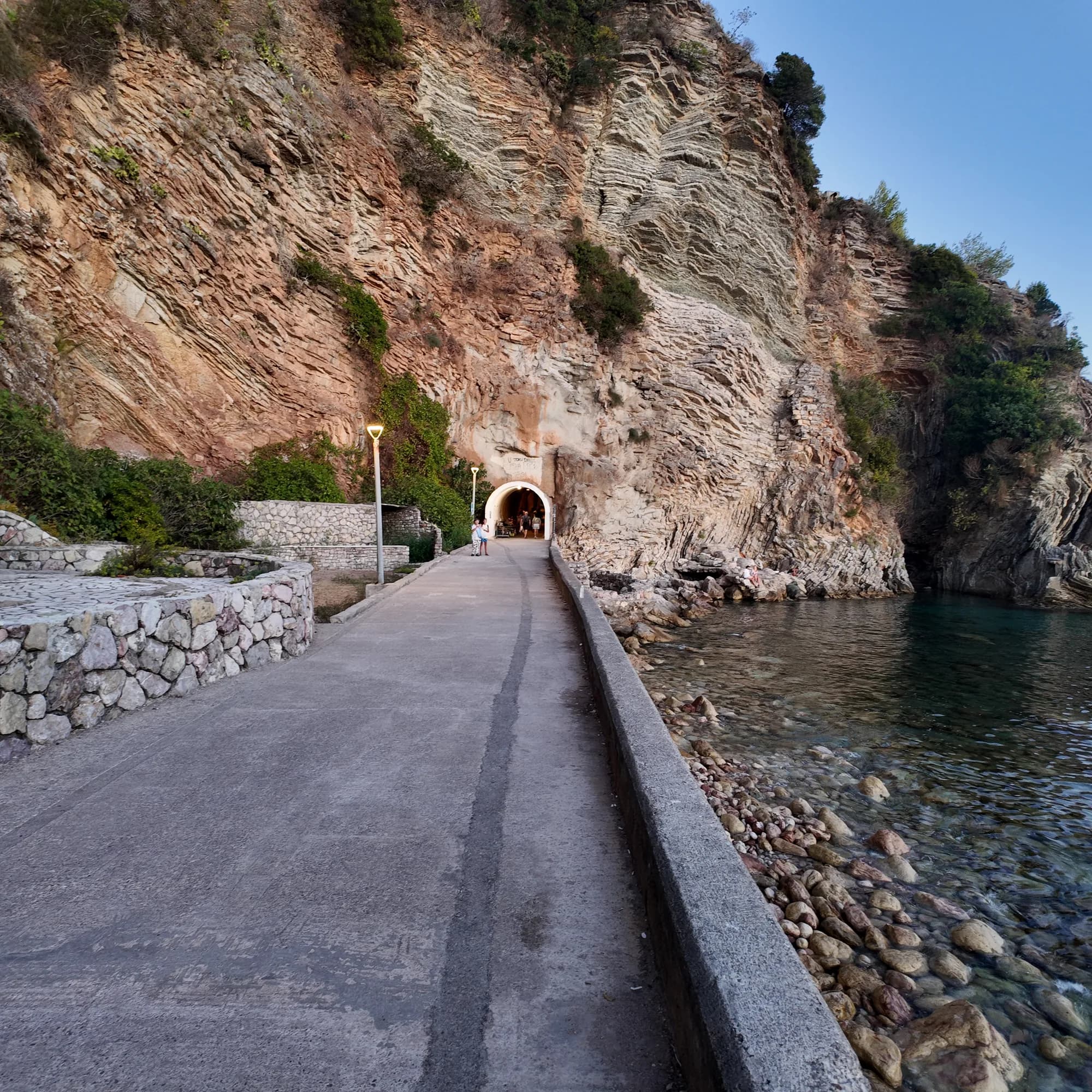 The concrete coastal path below the cliffs east of Rafailovići, leading to the mouth of the tunnel through the rock to Kamenovo
