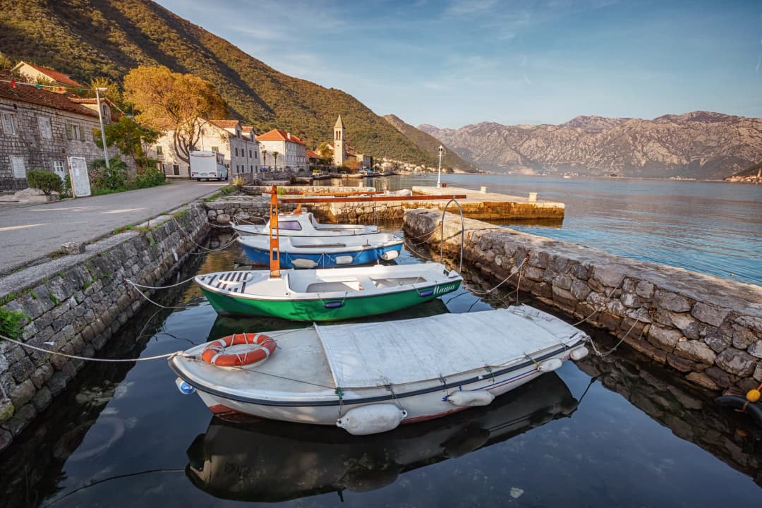 Stoliv's stone houses and terraced slopes rising from the water on the western shore of Kotor Bay.