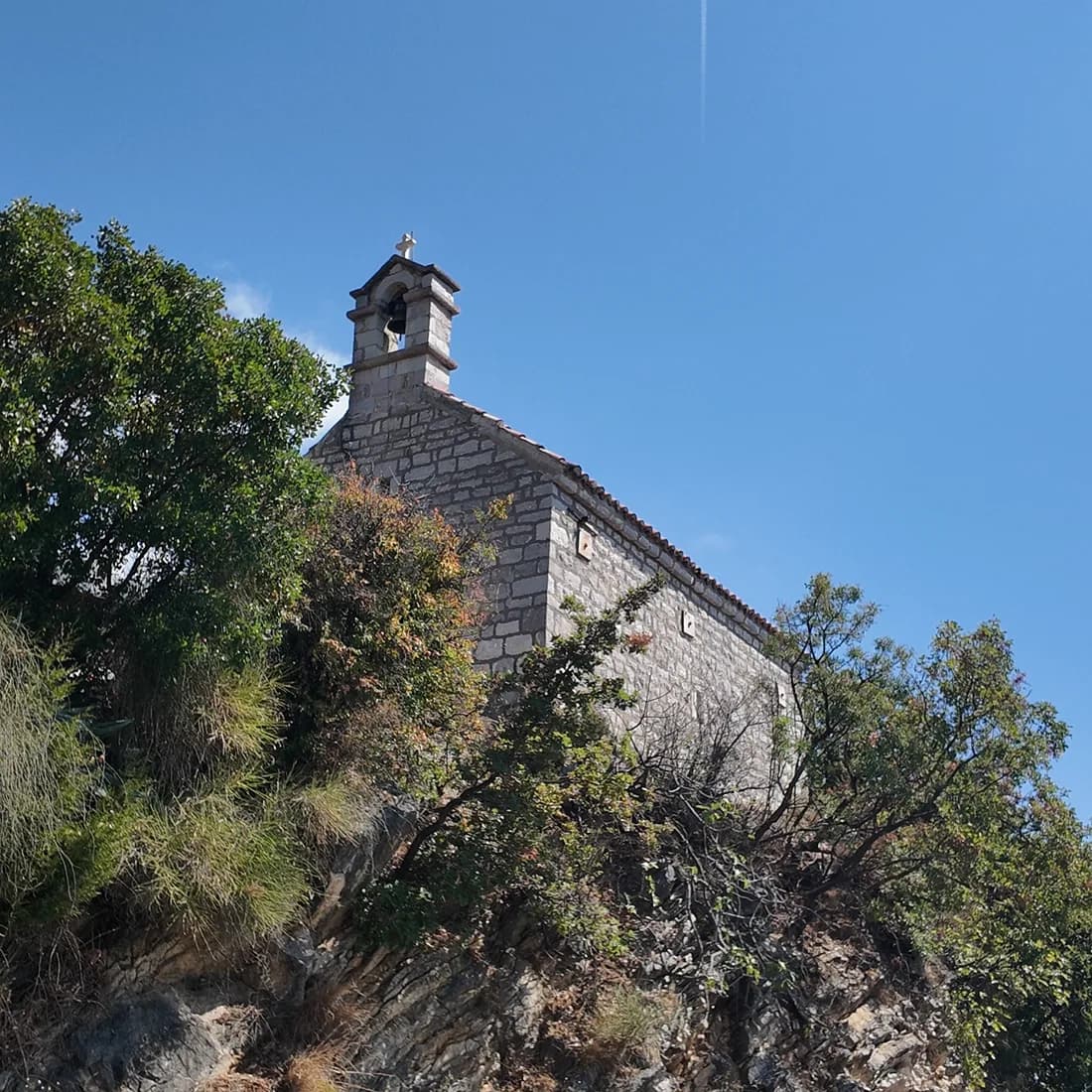 The church of Sveti Jovan on the slope above Sveti Stefan, the island below