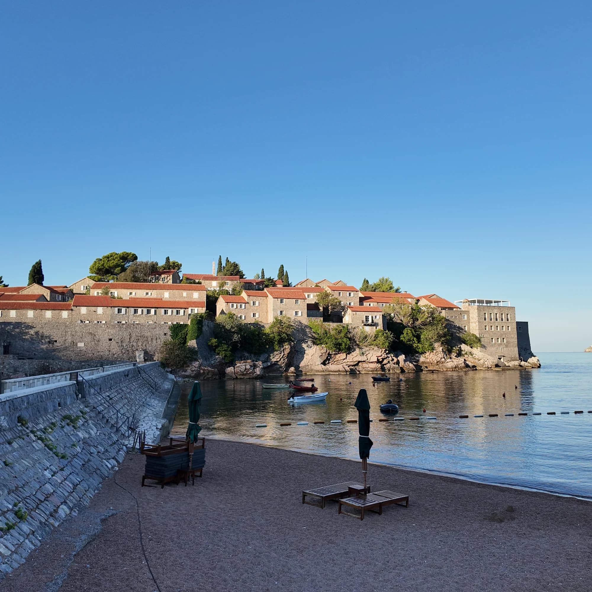 The stone walls and red roofs of Sveti Stefan catching the first warm morning sun
