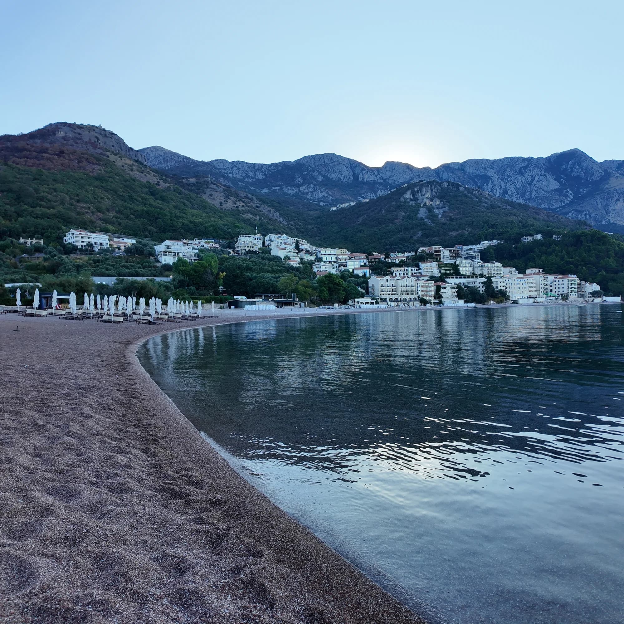 The curve of Sveti Stefan beach below the village and Paštrovići mountains at first light